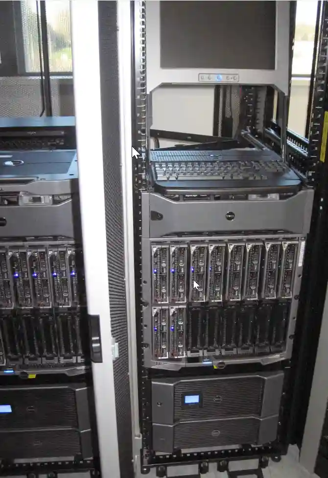 Server room racks filled with multiple servers and a mounted monitor with keyboard in a school's IT infrastructure.